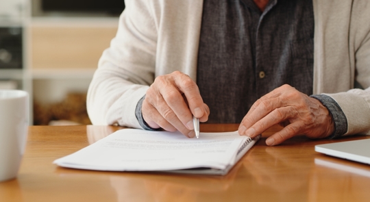 Hands of senior signing a document
